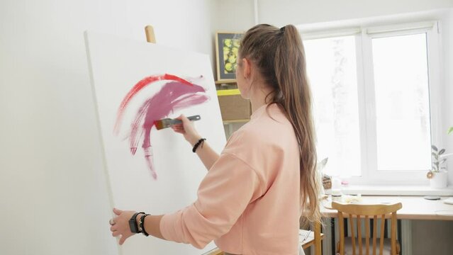 Talented female artist draws on canvas. Contemporary painter creating modern abstract picture. Art therapy. Young woman painter drawing picture on canvas using acrylic paints. 4K, UHD