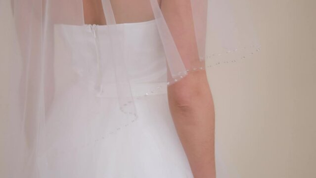 Close-up portrait of a bride in a dress with a veil that covers her head. Happy wedding day.