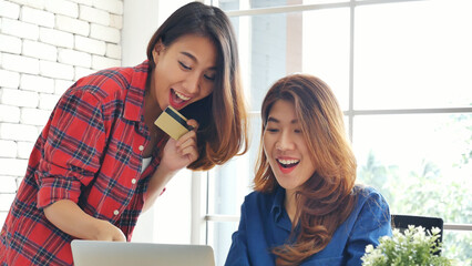 Two friends shopping using credit card online shopping on website laptop e-commerce website with smiling face, happiness. Happy asian women using laptop shopping online buy, payment newnormal concept - obrazy, fototapety, plakaty