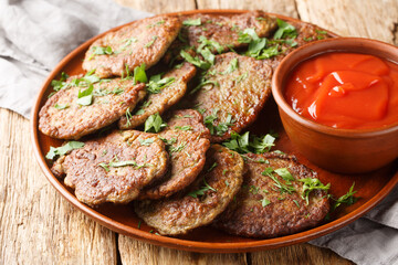Spicy liver pancakes served with tomato sauce and herbs close-up in a plate on the table. Horizontal