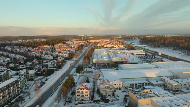 Golden sunrise in suburb of polish city in winter. Snow covered roof of factory and housing area in background. Aerial birds eye shot.