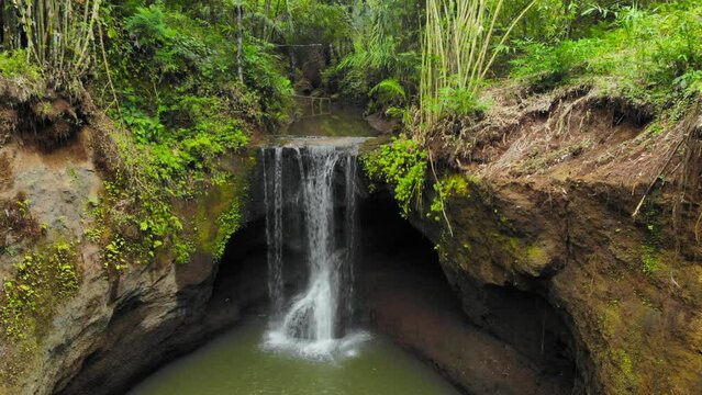Suwat Waterfall nestled in rainforest in Bali, Indonesia. Aerial footage captures the serene charm of this hidden gem. Ideal for travel, adventure, and natural wonders projects.