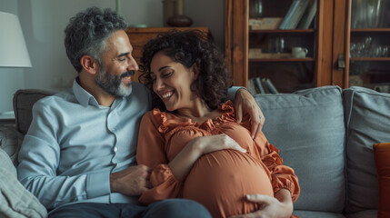 A couple shares a tender moment on a sofa, with the woman showing her pregnancy, both smiling and expressing joy and anticipation for their future child. - obrazy, fototapety, plakaty