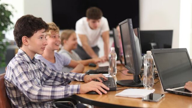 Focused teenager studying with classmates in modern school classroom