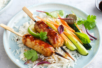 Tasty Asian-style chicken kebabs with rice, vegetables and teriyaki sauce, close-up.