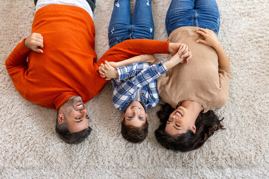 Happy family father, mother and cute son boy lying on floor