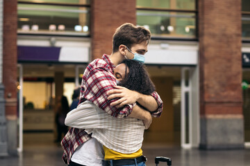Reunited at last!: Young couple meeting at the station after a trip - obrazy, fototapety, plakaty