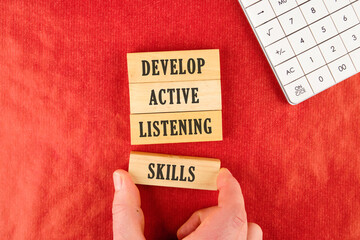 Concept word Develop active listening skills. Wooden blocks. Beautiful red background. The...