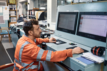 Engineer monitoring working parameters of equipment on the engine control room console.