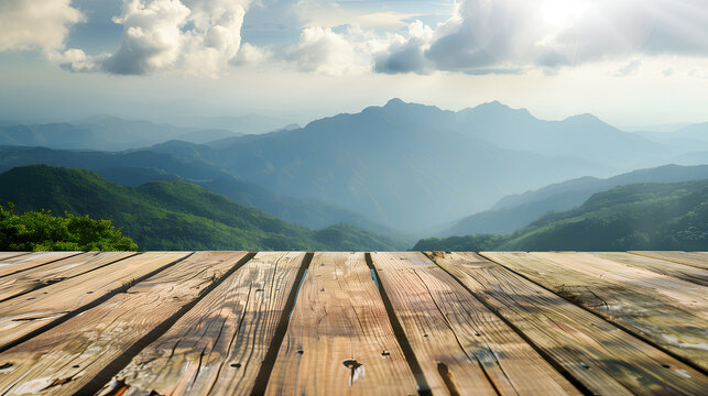 A wooden deck overlooking a mountain range with a clear blue sky. The view is serene and peaceful, with the sun shining brightly on the mountains. The wooden deck is a perfect spot to relax