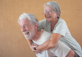 Image of cheerful senior couple having fun together while husband piggyback his wife, happy retirement lifestyle