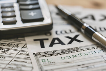 "Tax" title on newspaper, pen and calculator on the table. Tax concept.
