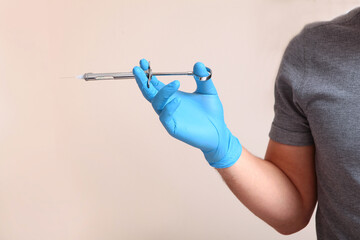 A nurse's hand in a medical glove holds a syringe with liquid. A syringe for injection. The concept of modern dentistry. Close-up. Space for text.