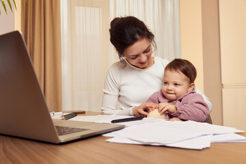 Fototapeta na wymiar Cheerful pretty businesswoman working at home with her little child girl