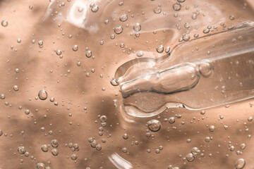 Cosmetic gel with a dropper close-up on a beige background, top view. Beauty background with...