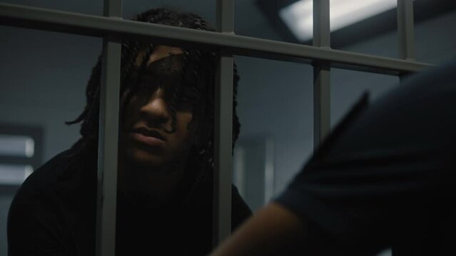Warden takes off handcuffs from young prisoner. Multi ethnic teenagers serve imprisonment term in correctional facility or detention center. Young criminals in prison cell. Justice system. Close up.