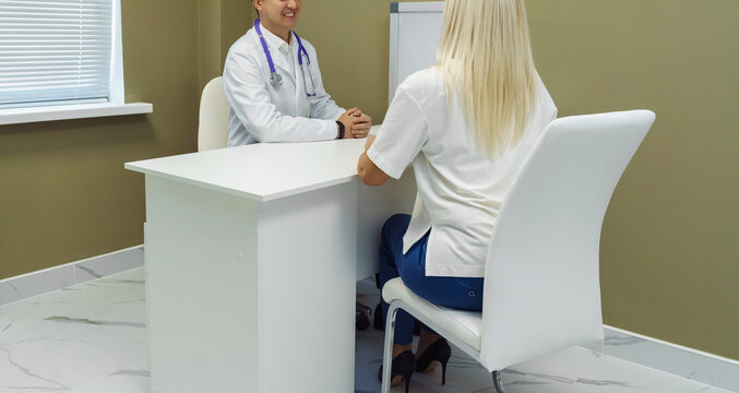Doctor consulting Patient. Professional physician wearing white coat talking to  woman at appointment visit in clinic.