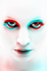 Beautiful and sexy looking woman close-up studio portrait. Model with smokey eye shadows and bright skin looking to camera with seductive look. Red and blue color split effect futuristic style
