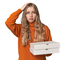 Blonde woman holding pizza boxes in studio being shocked, she has remembered important meeting.