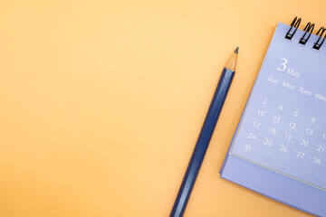 March Calendar and pencil isolated on orange background, planning for business meeting or travel...