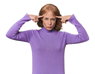 Redhead mid-aged Caucasian woman in studio focused on a task, keeping forefingers pointing head.