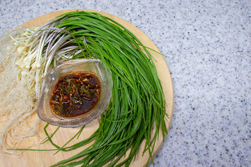Fresh Wild Chive vegetables and seasoning sauce and on a round wooden base. This seasoning sauce...