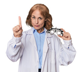 Mid-aged Caucasian optometrist in studio showing number one with finger.