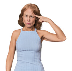 Redhead mid-aged Caucasian woman in studio pointing temple with finger, thinking, focused on a task.