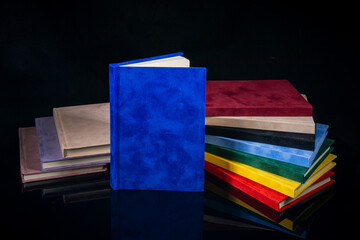 Fototapeta na wymiar Different colour notebooks on a black background