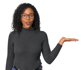 African American woman in studio setting impressed holding copy space on palm.