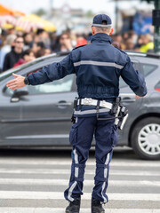 An Italian municipal policeman gestures towards traffic with polizia municipale on his uniform.Italy - Image- - obrazy, fototapety, plakaty