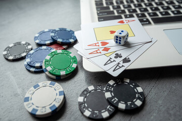 poker playing cards with casino chips on laptop keyboard for online gambling