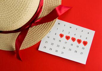Periods calendar and straw hat on red background.Concept of critical days,menstrual...