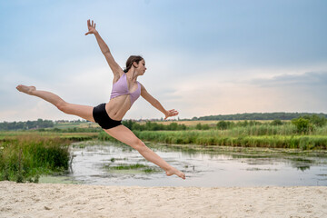 young fitness woman doing streching exercise on lake beach in summer