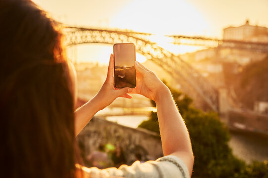 Woman photographing Dom Luis bridge through smart phone at Porto, Portugal