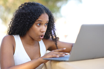 Amazed black woman checking laptop - 761245618