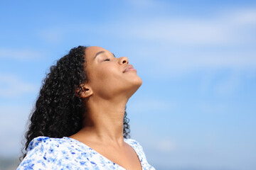 Black woman breathing fresh air with blue sky - 761245685