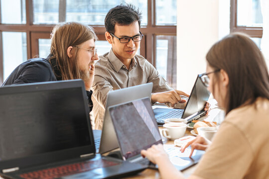 Programmers discussing over laptop near businesswoman working at startup
