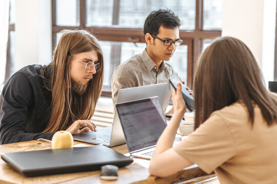 Team of programmers working on laptops at creative office