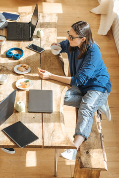 IT technician sitting with tea and cookies at table in startup office