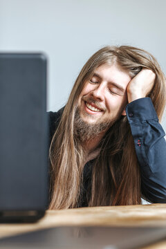 Smiling hipster programmer day dreaming by laptop at table in office
