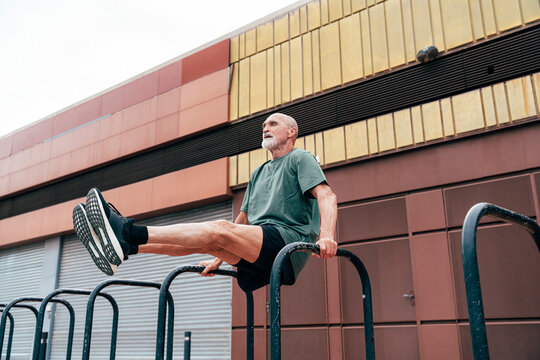 Active senior man exercising on parallel bars