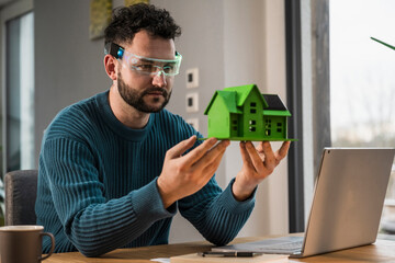 Architect wearing smart glasses and examining model house