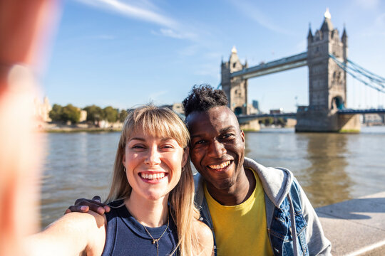 Happy multiracial friends taking selfie with Tower bridge in background