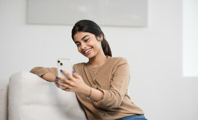 Young woman using smartphone at home. Student girl texting on mobile phone in her room. Communication, home work or study, connection, mobile apps, technology, lifestyle concept