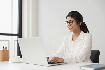 Young woman using laptop computer at office. Student girl working at home. Work or study from home, freelance, business, lifestyle concept
