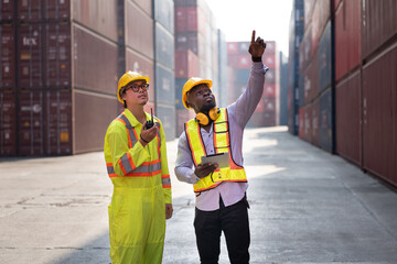 Portrait Asia logistic engineer man worker or foreman use walkie talkie working with African American foreman finger point with container background	 - 761260414