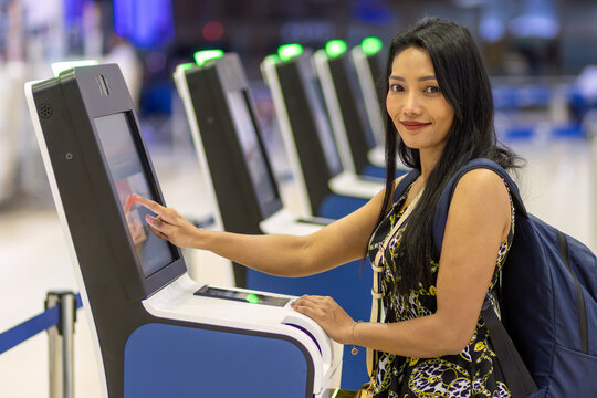 Young Asian woman using self check-in kiosks in airport terminal.