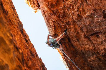 Woman rock climbing on orange rock face
