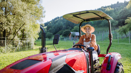 Progressive female farmer driving tractor on her own farm.